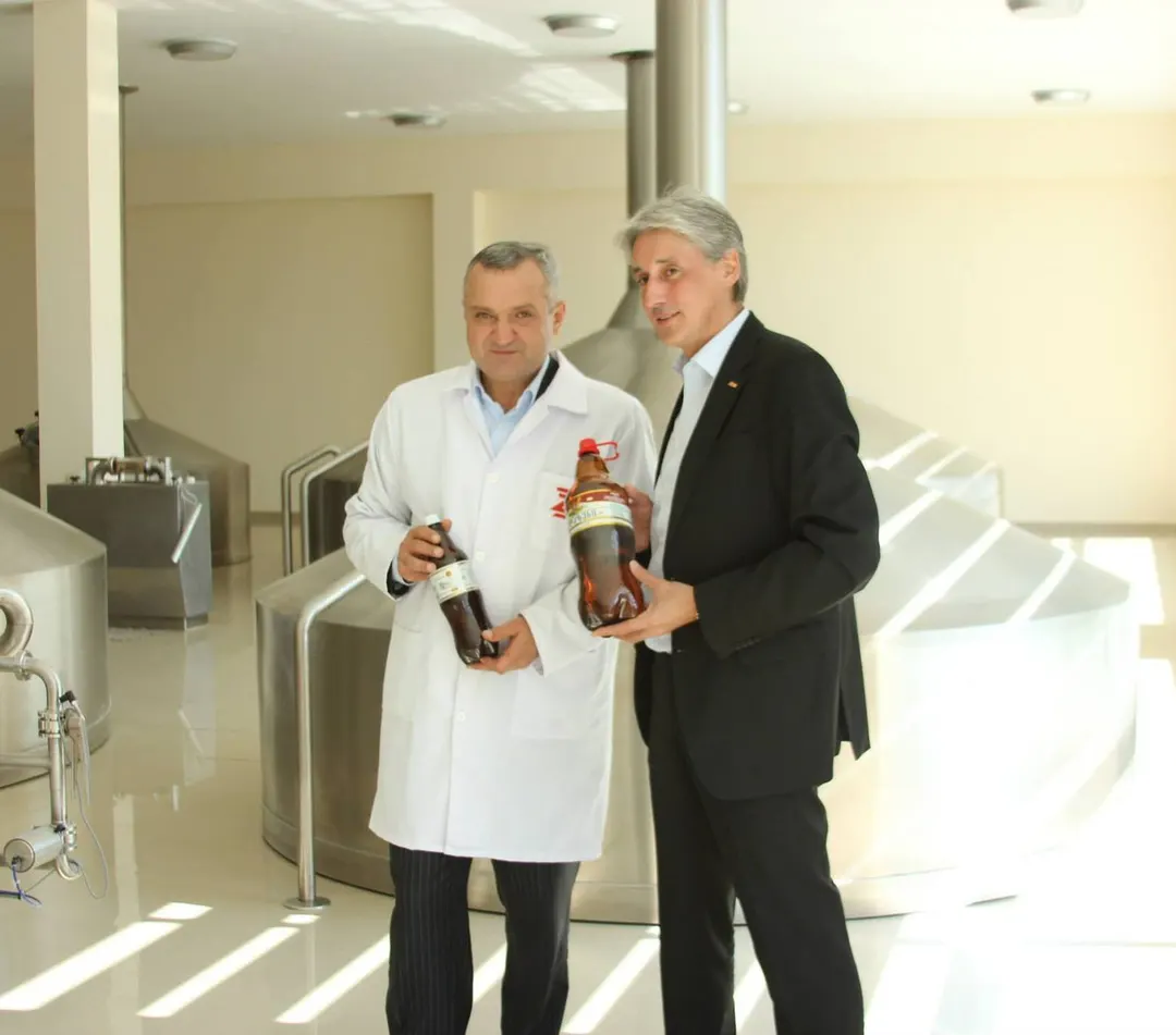 Tsezar Chocheli and a guest holding bottles in a brewhouse